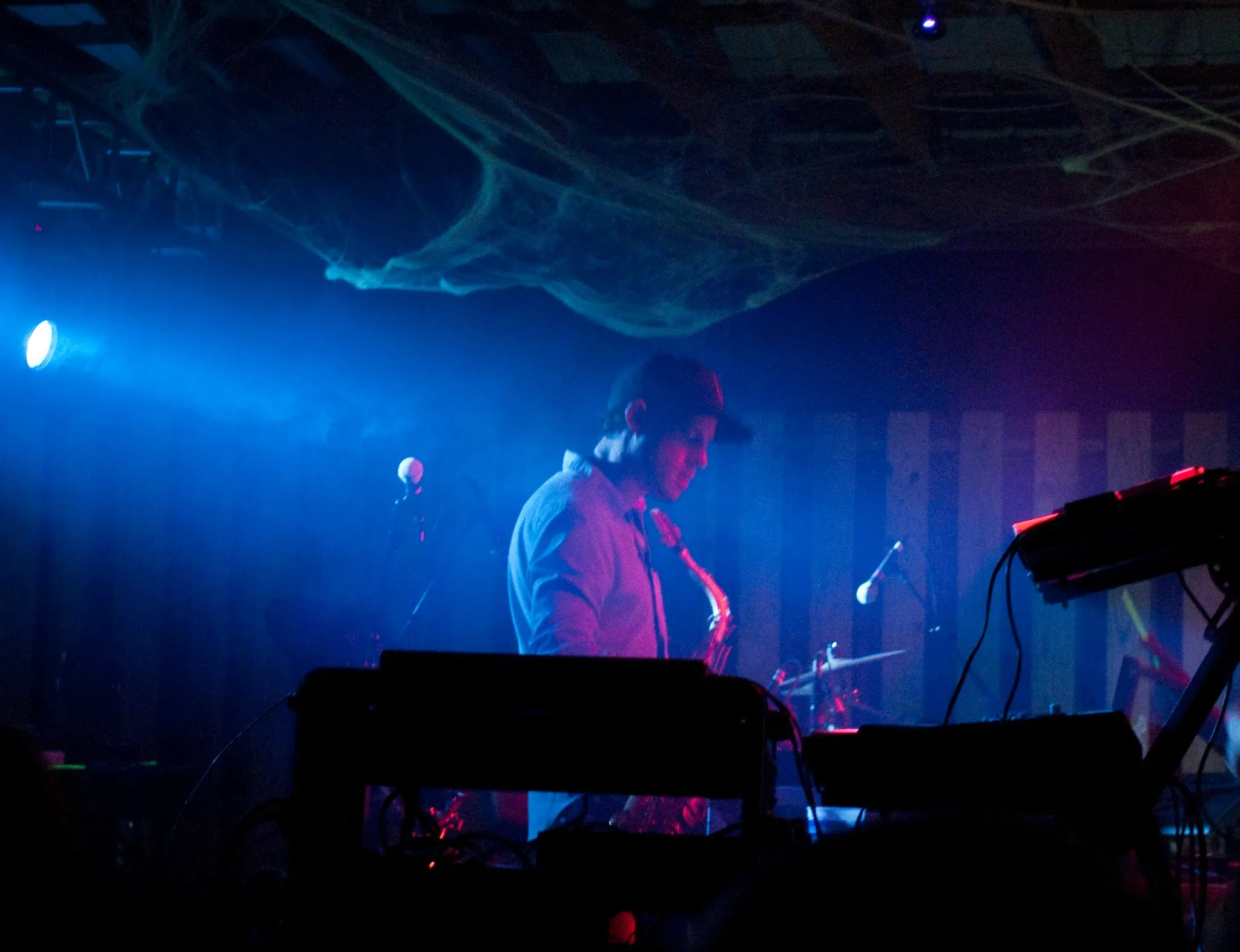 A profile of a man on stage with a saxophone. The light tints everything blue.