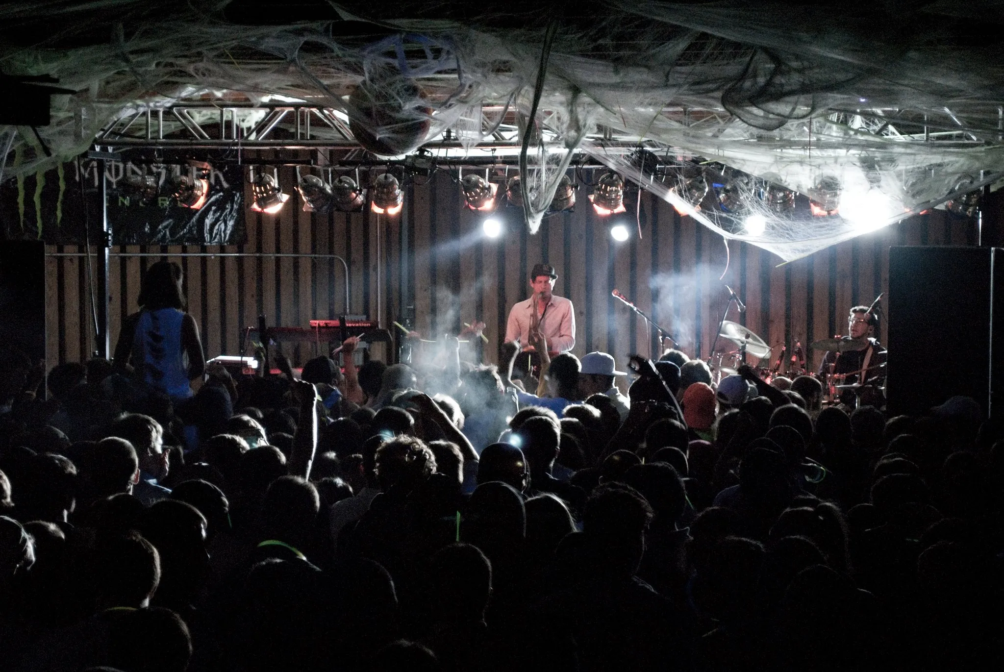 A man plays the saxophone on stage with the lights behind him.