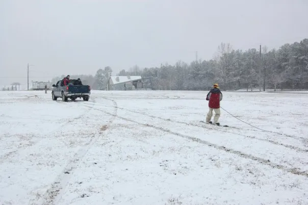 Andrew tries snowboarding while being pulled by a truck.