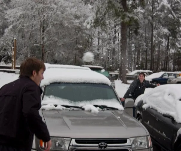 Brothers having a snowball fight in the parking log.