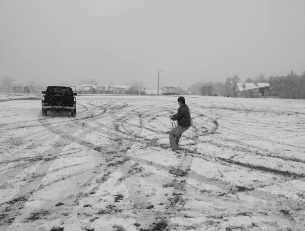 Someone is pulled behind a truck on a snowboard.