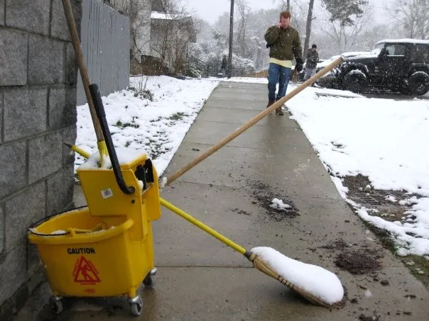 A mop bucket left out in the cold with a frozen mop.