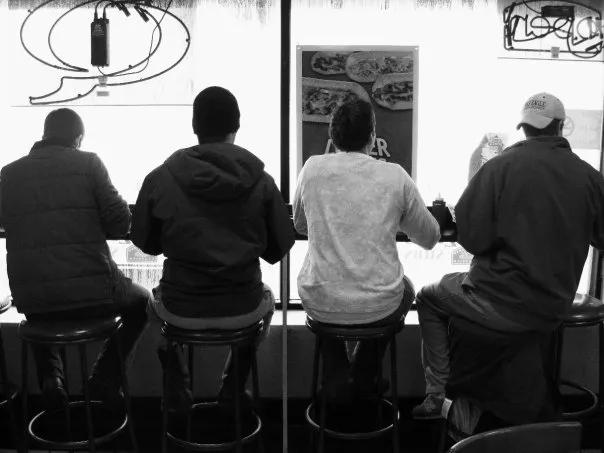 Four friends face out the window counter at Quizznos.