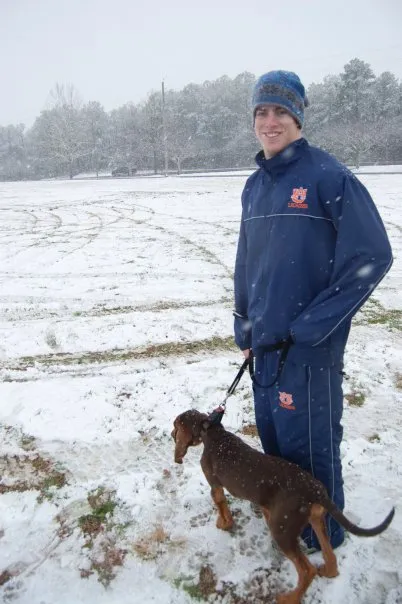 Kenny poses with a dog in the snow.