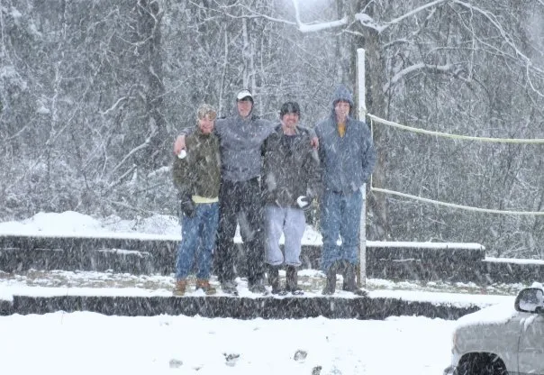 Friends pose infront of a volleyball net in the snow.