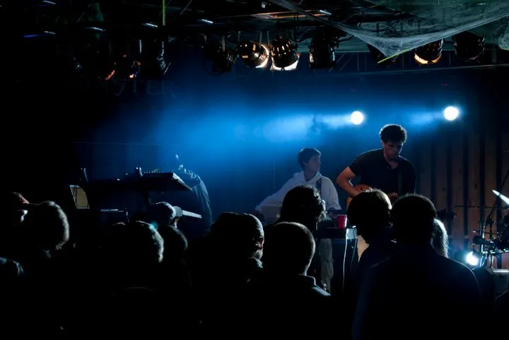 Blue lights shine through smoke while the band plays on stage.
