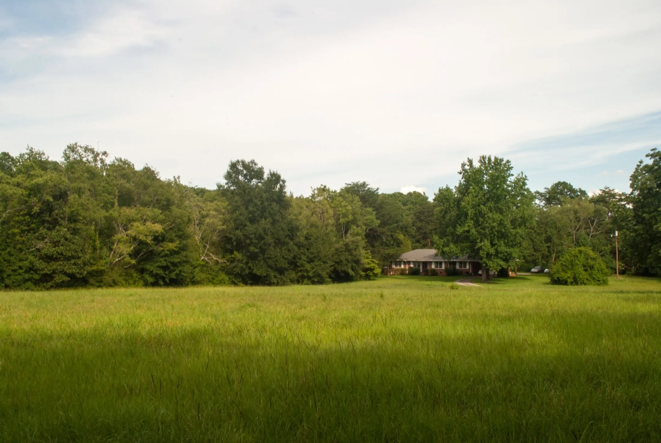 A field in the country with a small brick house in the distance.