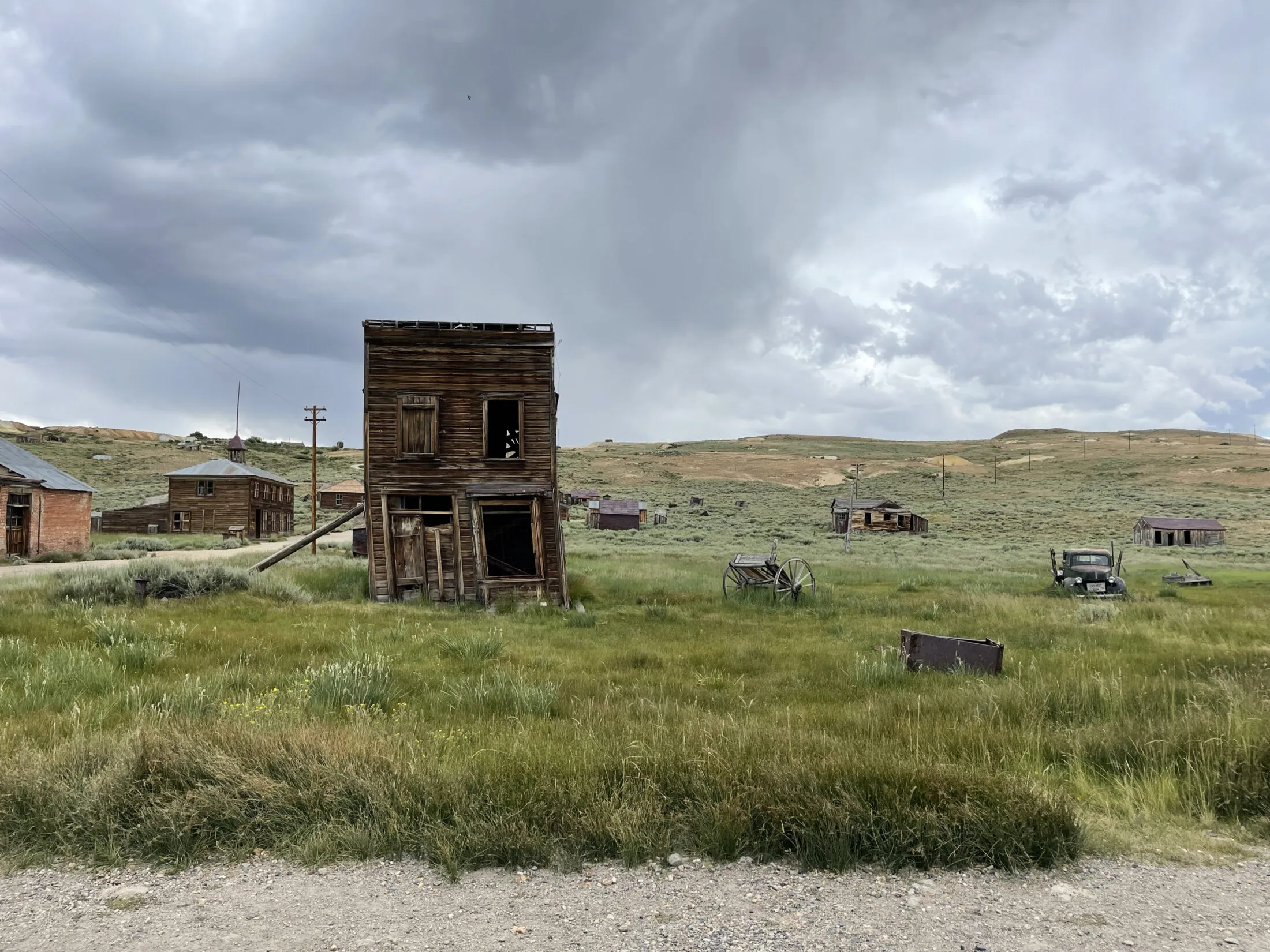 An old building in a field has a support beam holding it up.