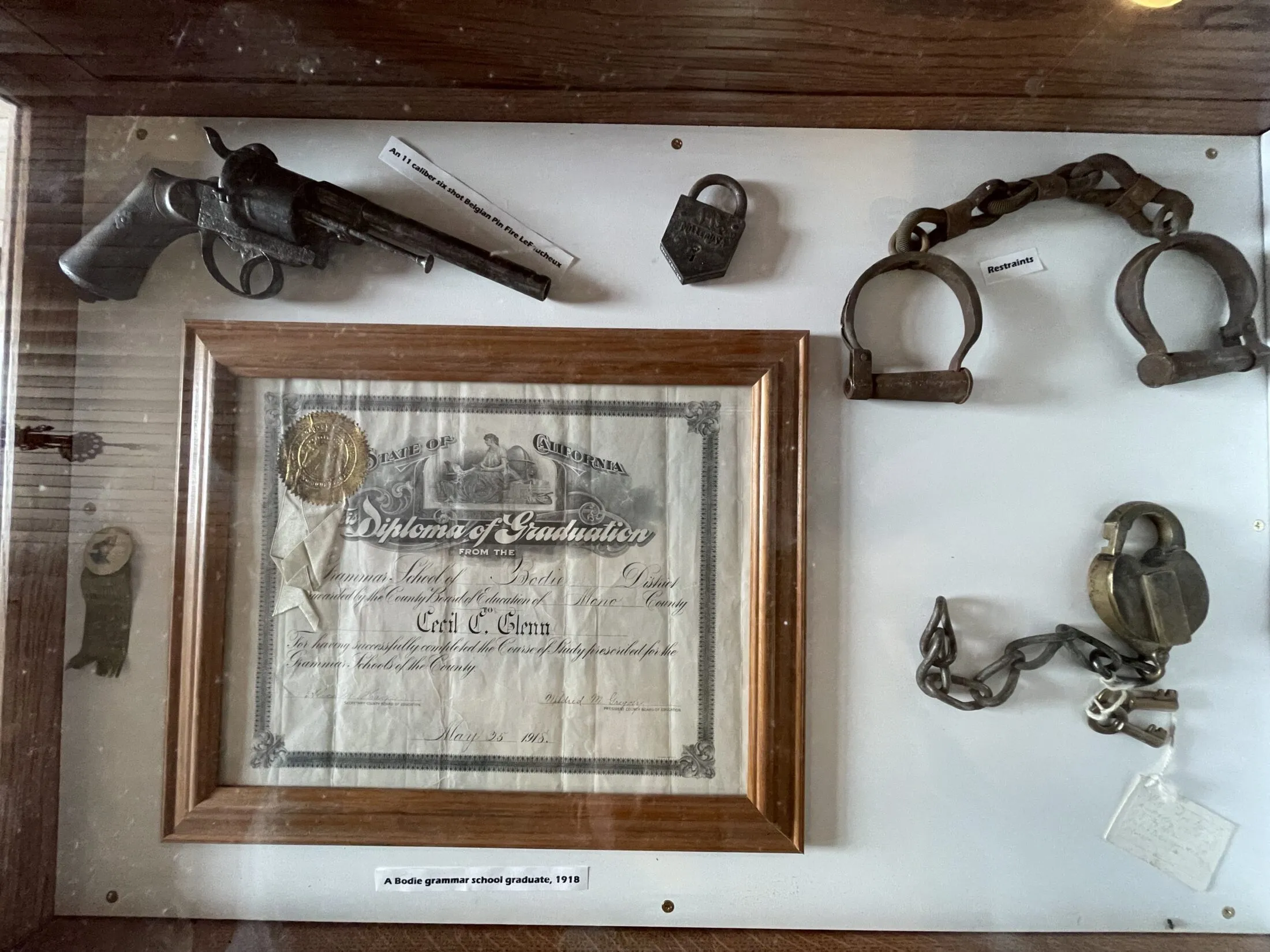A pistol and some random items in a glass case.