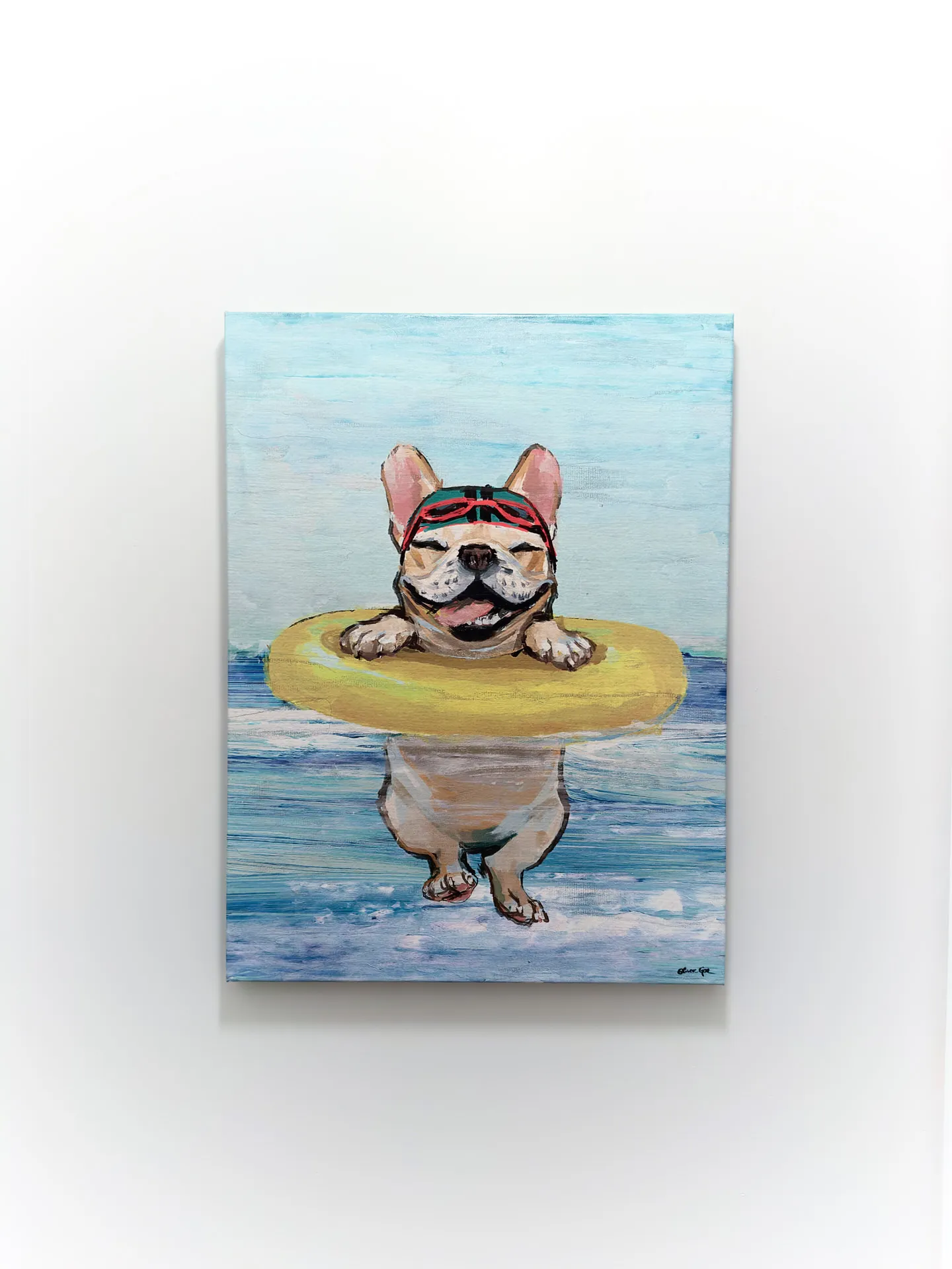 A whimsical painting of a bulldog wearing a red headband and sunglasses, floating serenely on a yellow inner tube on a body of water. The artwork, hanging on a white wall, exudes a playful and relaxed summer vibe.
