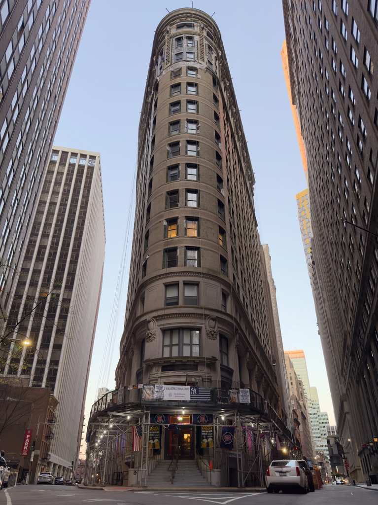 A street-level view of a rounded historic tower framed by tall office buildings.